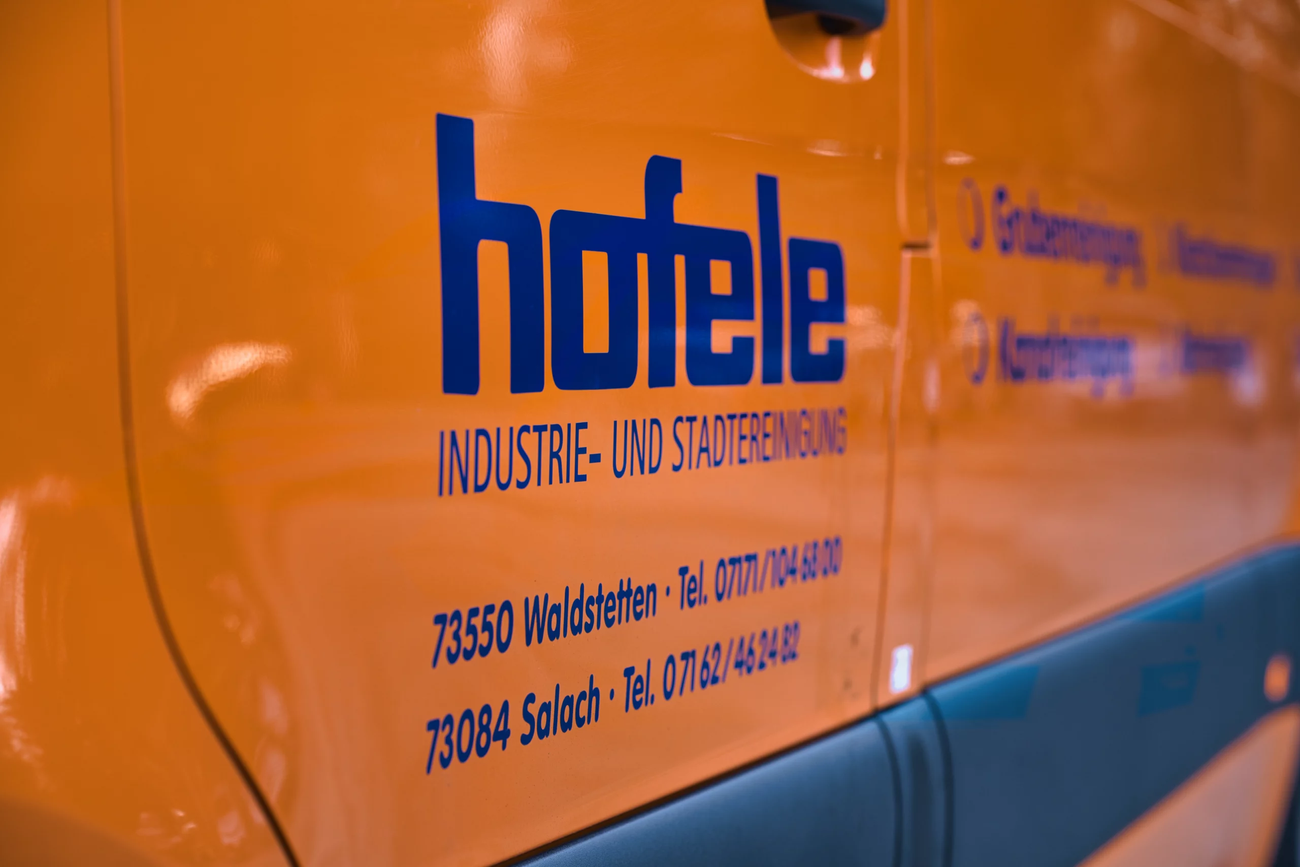 Hofele Logo im Detail auf einem Fahrzeug Detailaufnahme der Hofele Fahrzeugbeschriftung auf orangefarbenem Einsatzfahrzeug